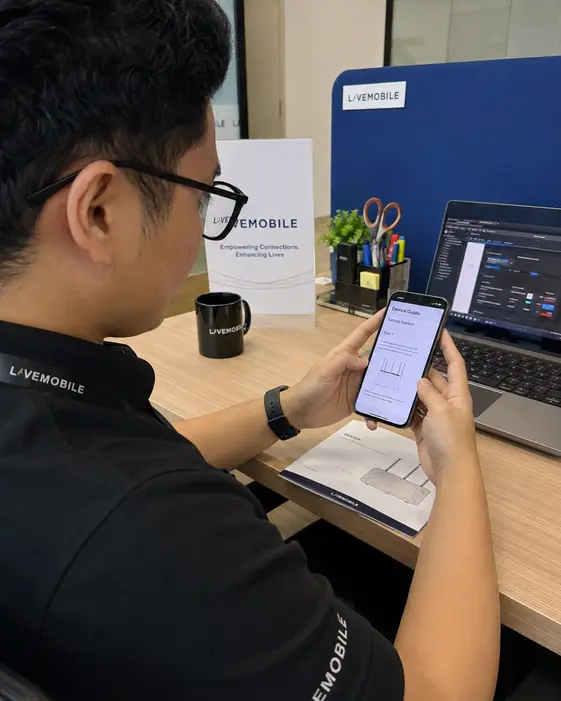 Seorang ahli pasukan menguji paparan panduan pada telefon di hadapan komputer riba